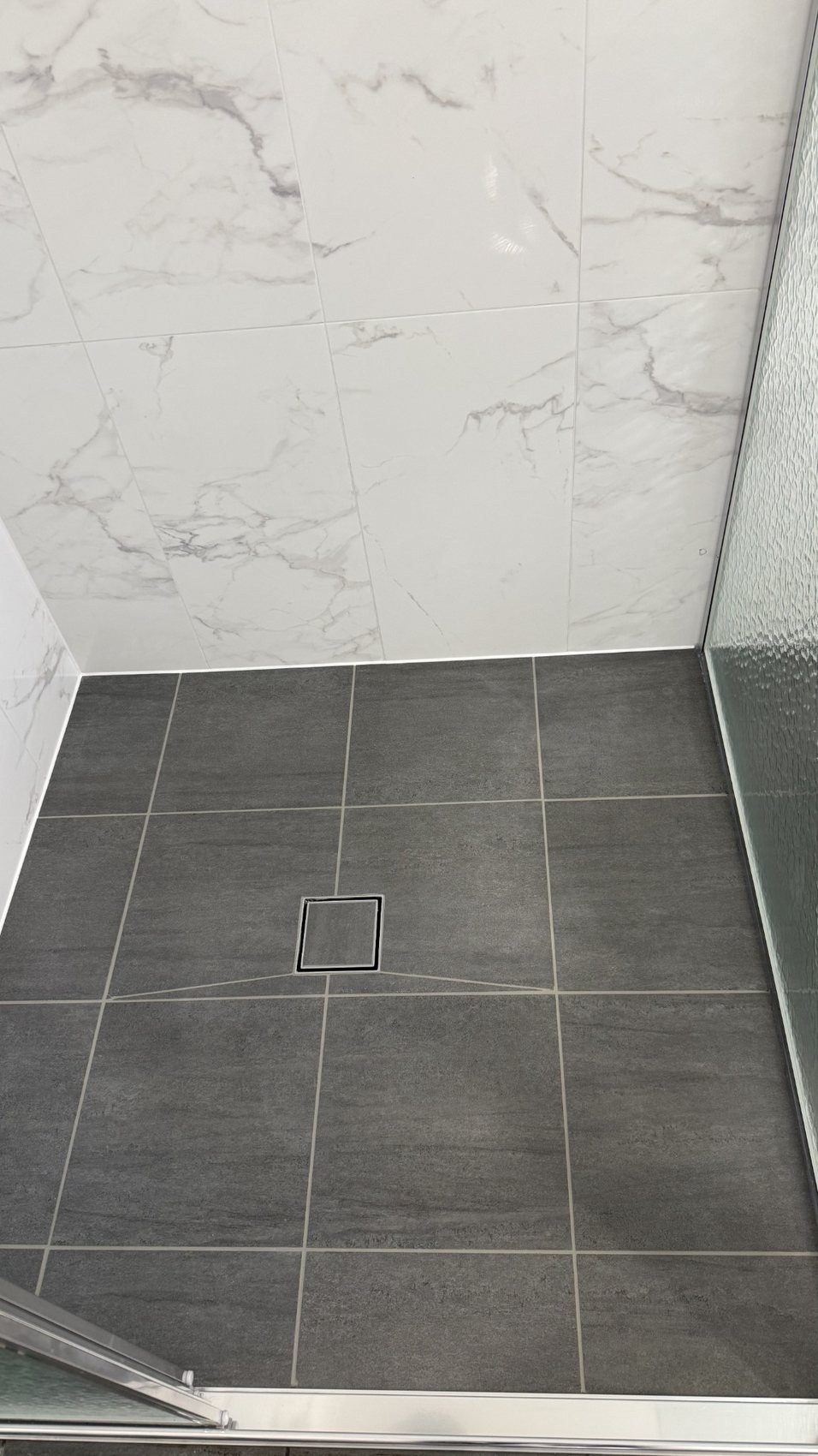 Shower with marble-look wall tiles and dark tiled floor