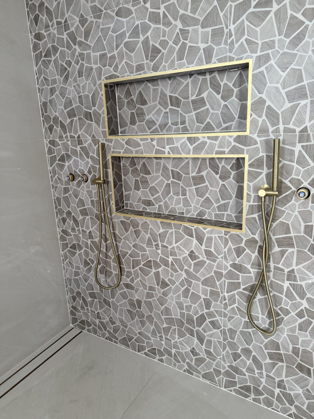 Mosaic tiled shower wall with niches and detailed sealant joints