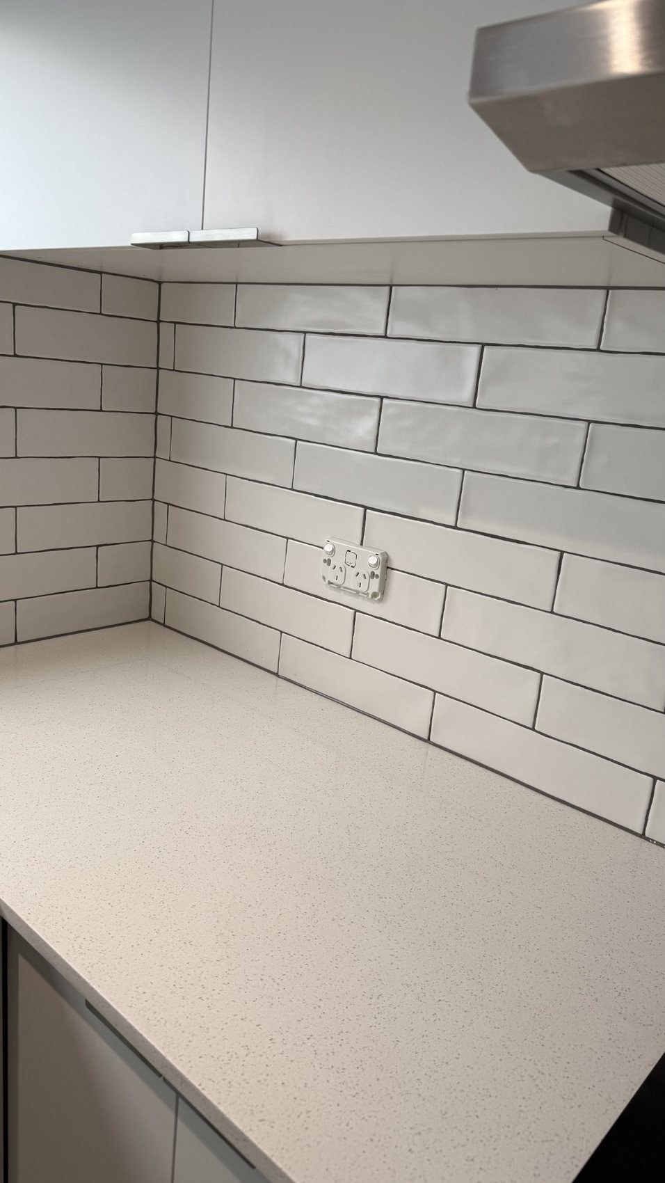White kitchen benchtop and tiled splashback with clean caulking lines